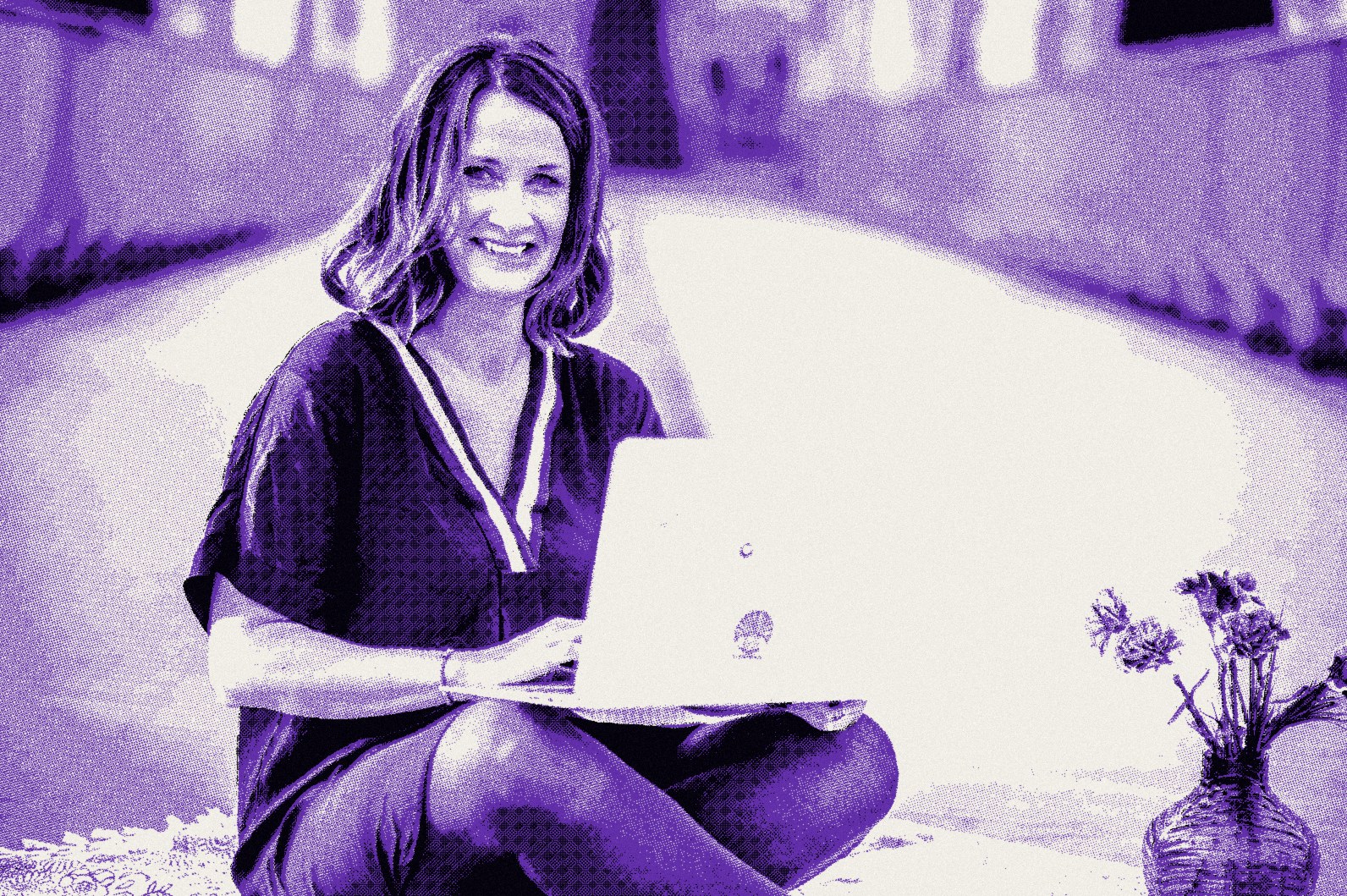 Raphaela Ayriss sitzt lachend im Schneidersitz auf einer Brücke, den Laptop auf dem Schoß
